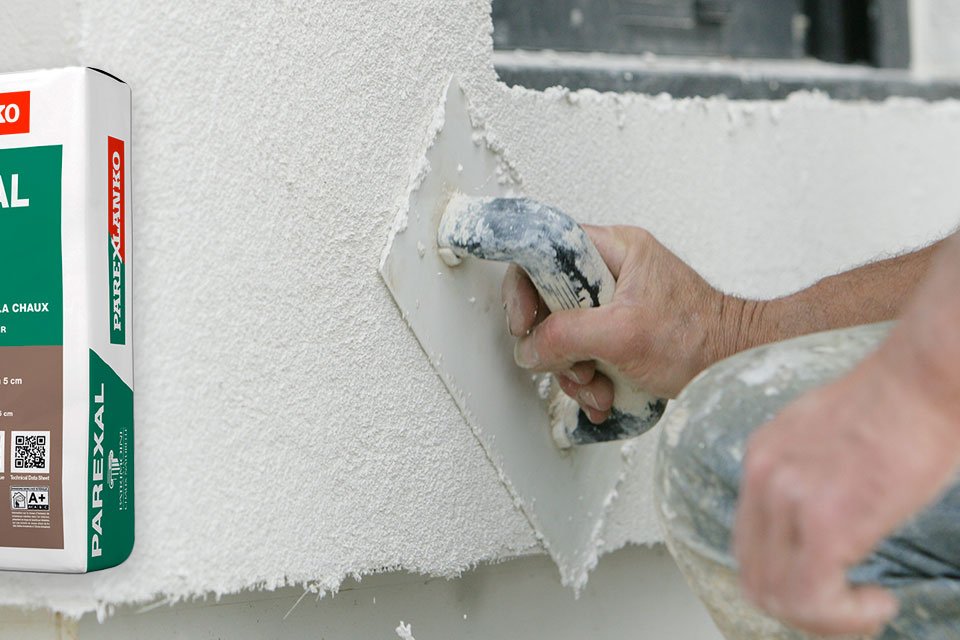 Professionnel appliquant de l'enduit sur une façade